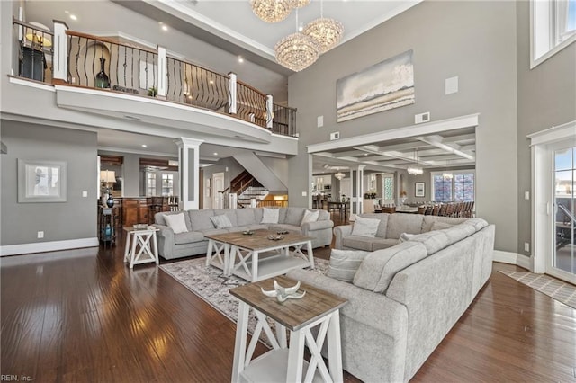 living room with a notable chandelier, a high ceiling, beam ceiling, and dark hardwood / wood-style flooring