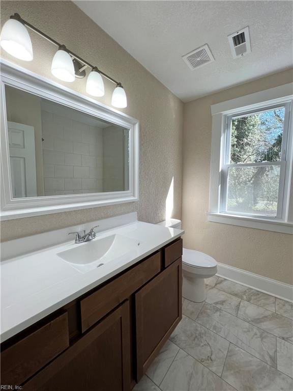 bathroom with vanity, toilet, and a textured ceiling