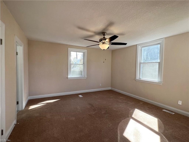 empty room with dark colored carpet, ceiling fan, and a textured ceiling