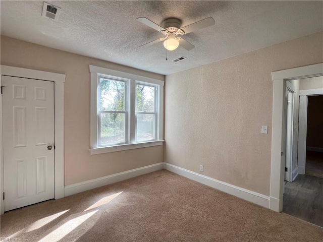 empty room with carpet, ceiling fan, and a textured ceiling