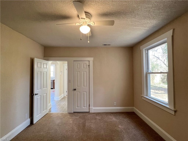 carpeted empty room with ceiling fan and a textured ceiling