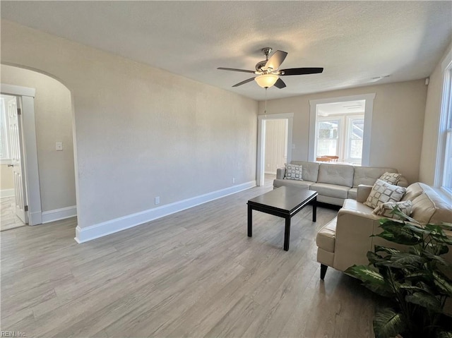 living room with light hardwood / wood-style floors, ceiling fan, and a textured ceiling