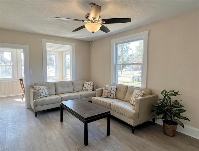 living room featuring ceiling fan, a textured ceiling, light hardwood / wood-style flooring, and a healthy amount of sunlight