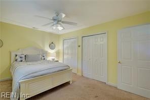 carpeted bedroom featuring multiple closets and ceiling fan