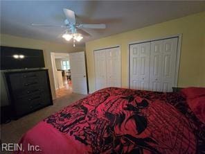 carpeted bedroom featuring ceiling fan and two closets