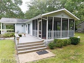 rear view of property featuring a sunroom and a lawn