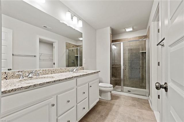 bathroom with tile patterned flooring, a shower with door, vanity, and toilet