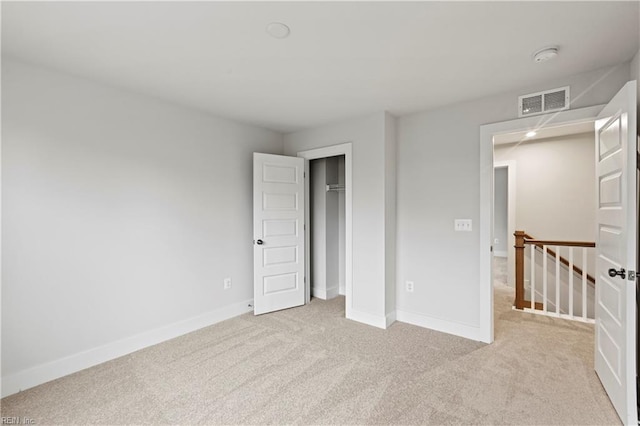 unfurnished bedroom featuring light colored carpet and a closet