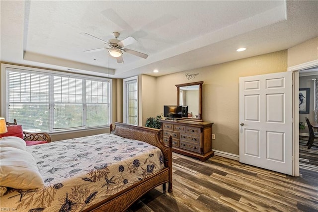 bedroom featuring a textured ceiling, a raised ceiling, dark hardwood / wood-style floors, and ceiling fan