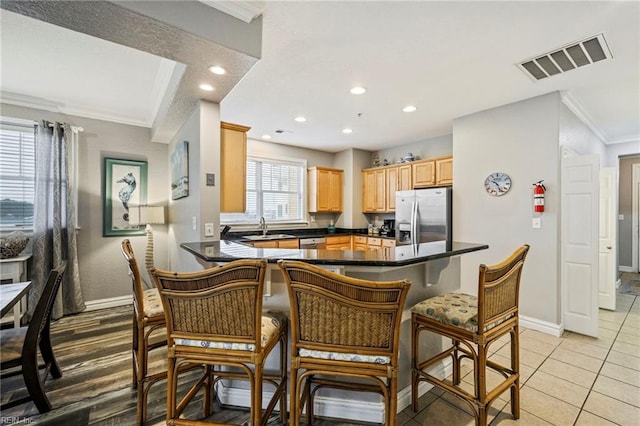 kitchen featuring sink, kitchen peninsula, stainless steel appliances, light tile patterned floors, and crown molding