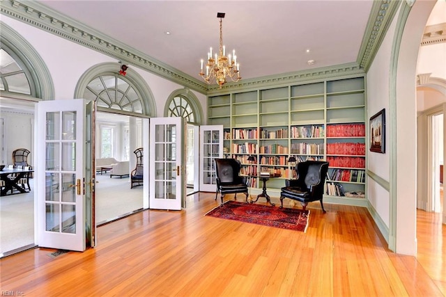 living area featuring built in shelves, hardwood / wood-style floors, french doors, and crown molding