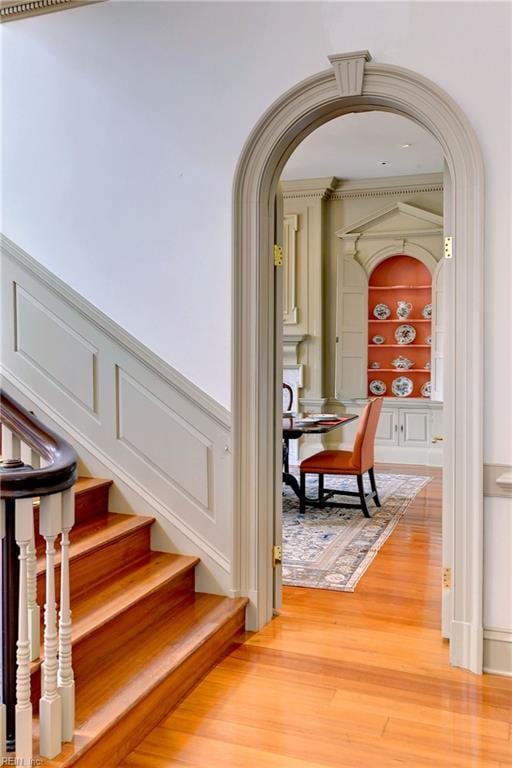 stairs with built in shelves, ornamental molding, and hardwood / wood-style floors