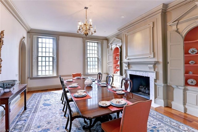 dining room with light hardwood / wood-style floors, a premium fireplace, a healthy amount of sunlight, and crown molding