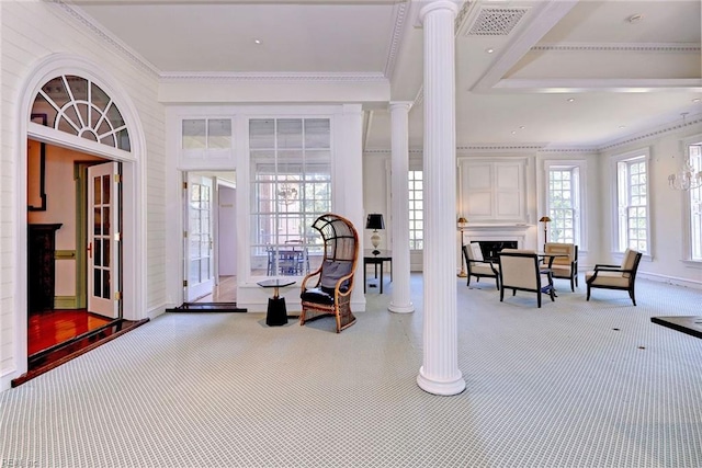 carpeted foyer entrance with crown molding and decorative columns