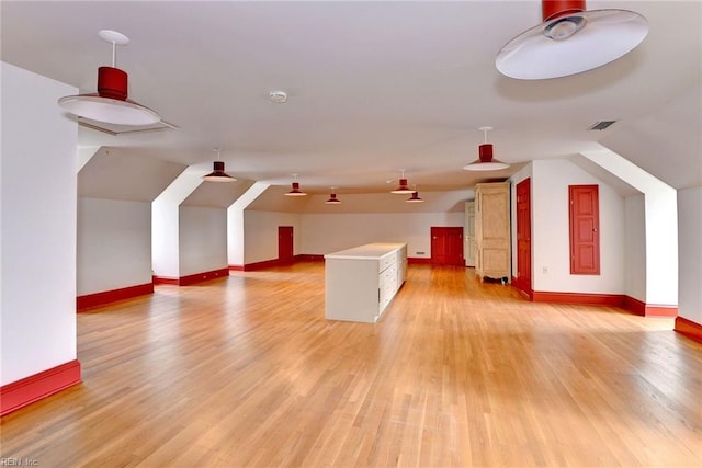 additional living space with light wood-type flooring and lofted ceiling