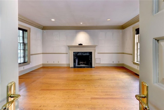 unfurnished living room with a high end fireplace, ornamental molding, and light hardwood / wood-style flooring