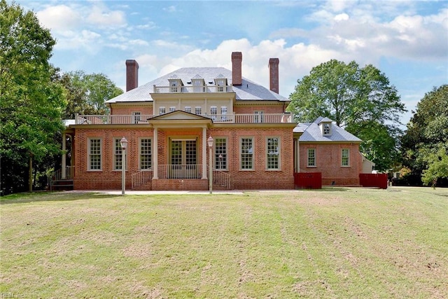 rear view of property featuring a balcony and a yard