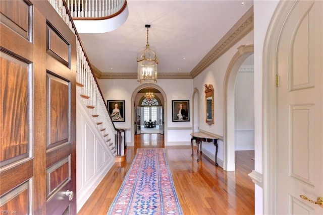 foyer featuring an inviting chandelier, light hardwood / wood-style flooring, and crown molding