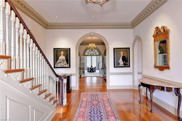 foyer entrance with an inviting chandelier, hardwood / wood-style flooring, and crown molding