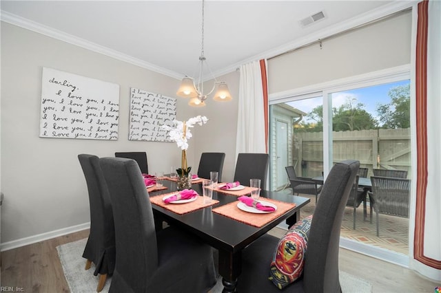 dining area with a notable chandelier, crown molding, and hardwood / wood-style floors