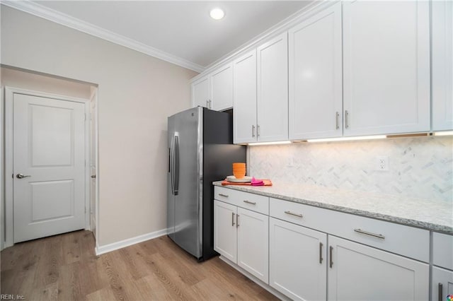 kitchen with ornamental molding, stainless steel fridge, light hardwood / wood-style floors, and white cabinetry