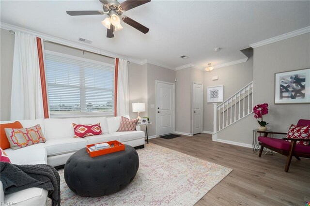 living room with light hardwood / wood-style floors, ornamental molding, and ceiling fan