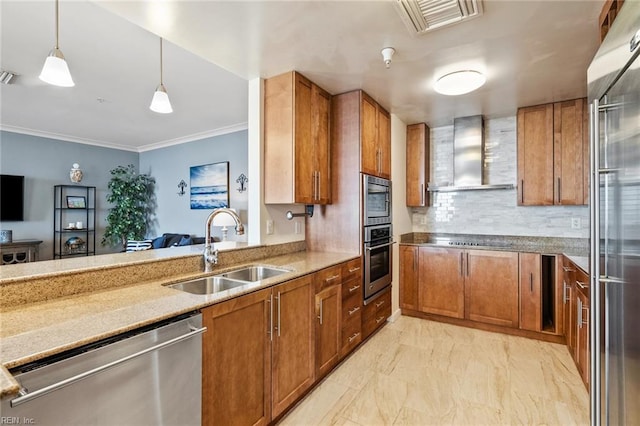 kitchen with pendant lighting, sink, wall chimney exhaust hood, appliances with stainless steel finishes, and crown molding