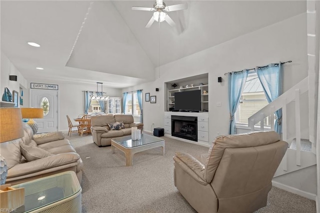 living room featuring light carpet, ceiling fan with notable chandelier, built in shelves, and a wealth of natural light