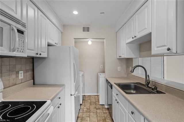 kitchen with independent washer and dryer, sink, white cabinets, and white appliances