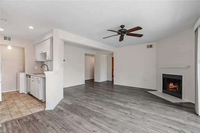 unfurnished living room featuring ceiling fan, sink, and light hardwood / wood-style floors