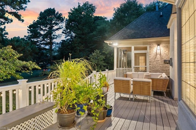 deck at dusk featuring a sunroom and an outdoor living space