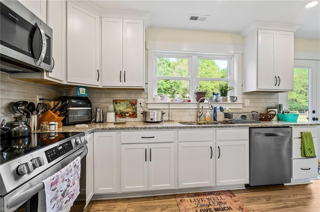 15338 Everets Rd, Windsor, VA 23487 - kitchen featuring appliances with stainless steel finishes, white cabinets, a sink, light stone counters, and backsplash
