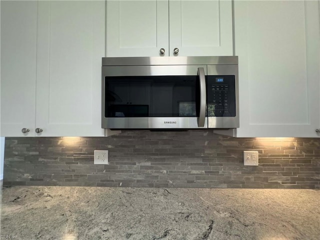 kitchen with decorative backsplash, white cabinetry, and light stone counters