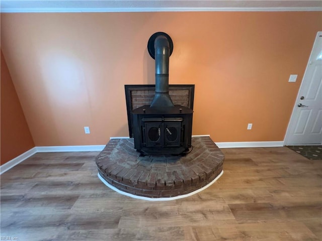 interior details featuring ornamental molding, a wood stove, and hardwood / wood-style flooring