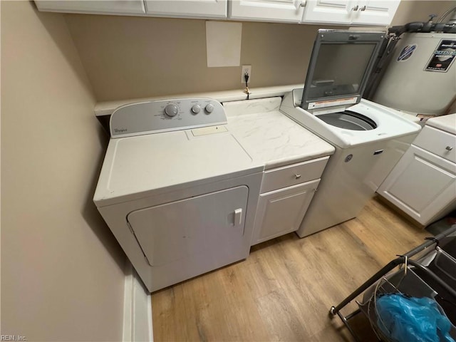 laundry room with cabinets, water heater, light hardwood / wood-style floors, and independent washer and dryer