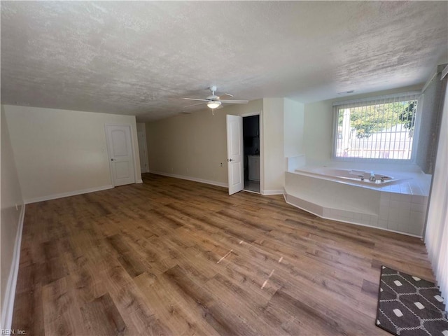 unfurnished living room featuring wood-type flooring, ceiling fan, and a textured ceiling