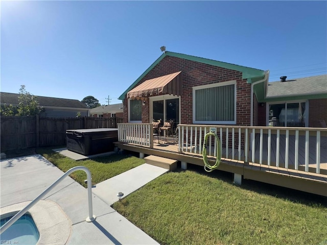 back of house featuring a deck, a lawn, and a hot tub