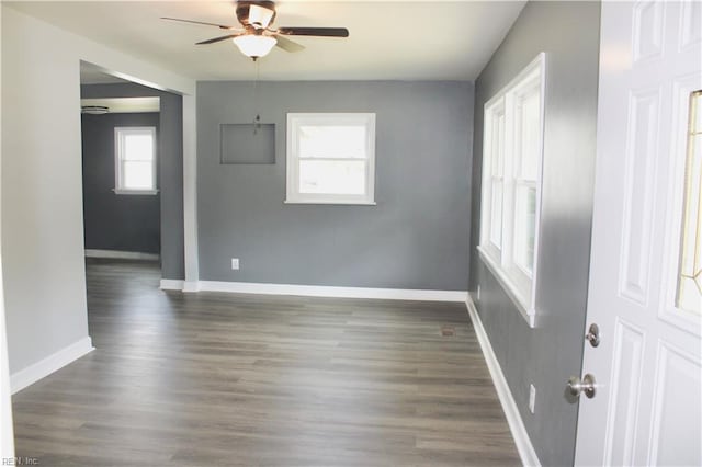 unfurnished room with ceiling fan, dark wood-type flooring, and a wealth of natural light