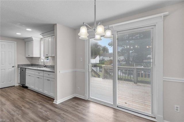 kitchen with dark hardwood / wood-style floors, sink, an inviting chandelier, decorative light fixtures, and stainless steel dishwasher