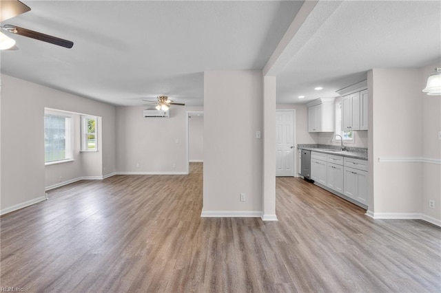 interior space with light hardwood / wood-style floors, light stone countertops, dishwasher, ceiling fan, and sink