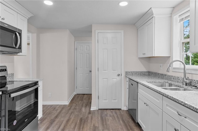 kitchen with wood-type flooring, sink, stainless steel appliances, and white cabinets