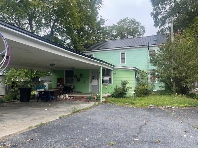 view of front of property featuring a porch, a carport, and cooling unit