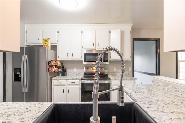 kitchen with light stone counters, white cabinets, and stainless steel appliances