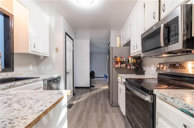 kitchen featuring appliances with stainless steel finishes, light hardwood / wood-style floors, light stone counters, and white cabinets