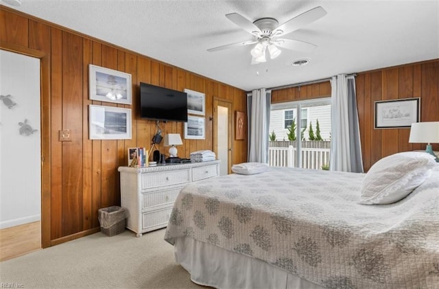 carpeted bedroom featuring access to outside, wooden walls, and ceiling fan