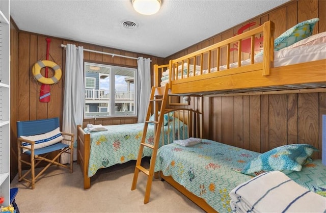 bedroom featuring carpet floors, wood walls, and a textured ceiling