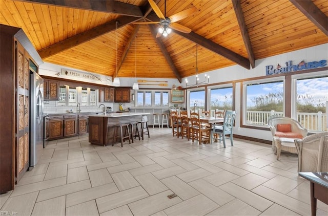 unfurnished dining area featuring ceiling fan with notable chandelier, high vaulted ceiling, beam ceiling, and wooden ceiling