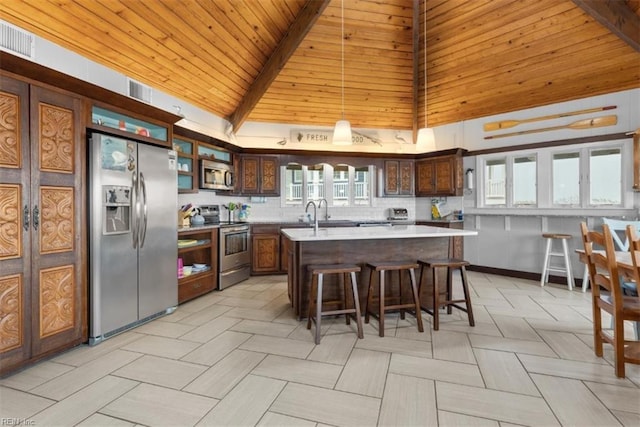 kitchen with high vaulted ceiling, appliances with stainless steel finishes, a kitchen island, and a wealth of natural light