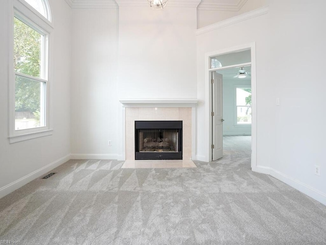 unfurnished living room featuring ceiling fan, light colored carpet, crown molding, and a tile fireplace