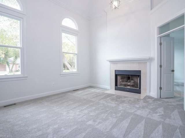 unfurnished living room featuring light carpet, plenty of natural light, ornamental molding, and a tile fireplace